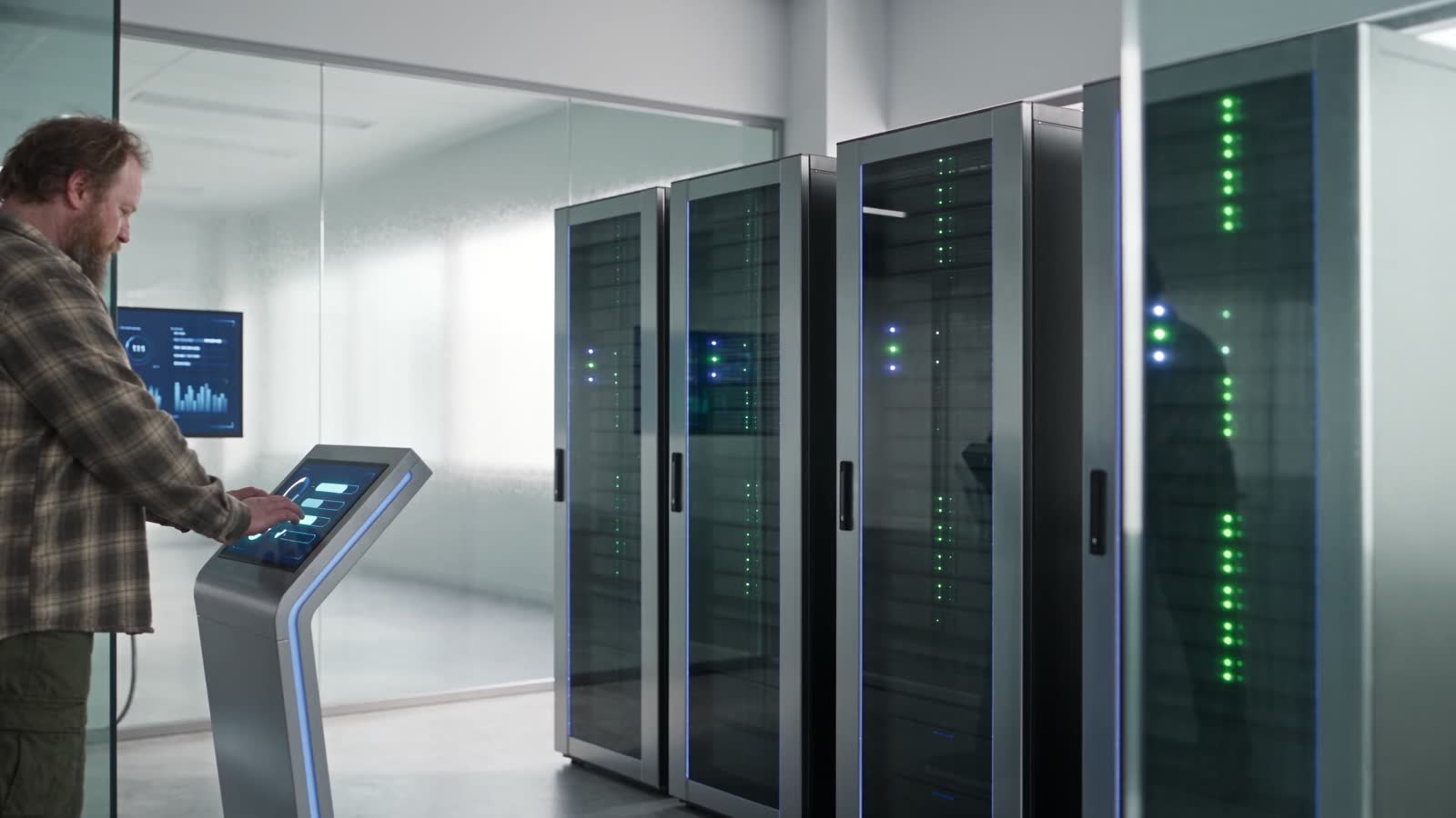 A row of server racks with green status LEDs, seen past a standing console on the operations floor.